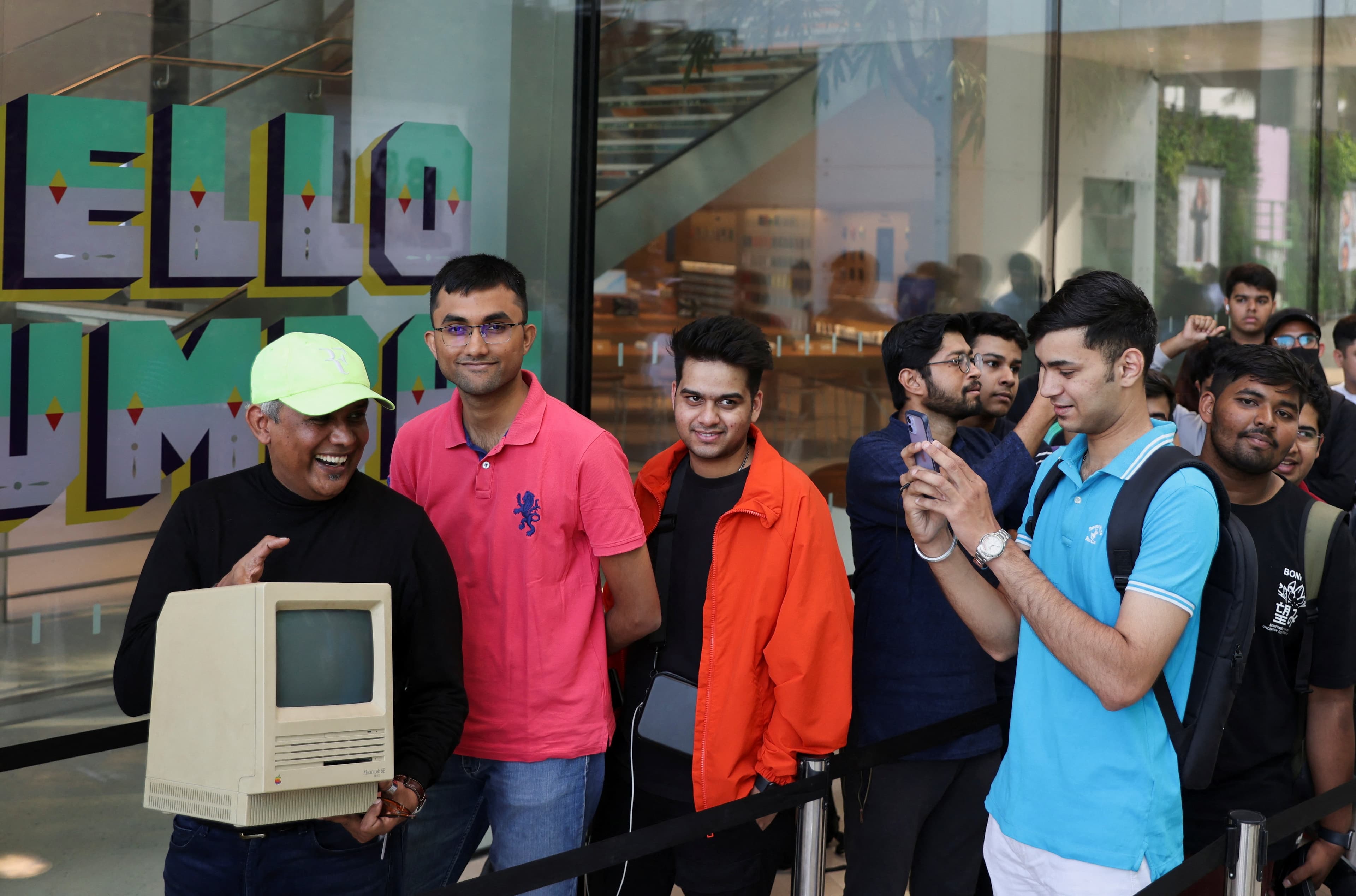 Apple Store BKC opening : An Apple fan takes a photo of Sajid Moinuddin as he poses with a Macintosh SE computer while waiting in a queue outside India's first Apple retail store. (REUTERS)