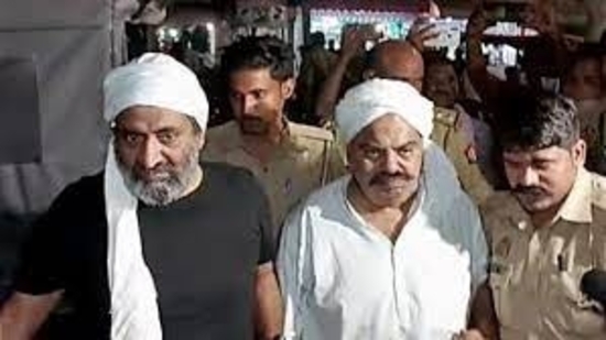 Police personnel escort Mafia-turned-politician Atiq Ahmad for a medical examination, in Prayagraj. Atiq's brother Khalid Azim alias Ashraf also seen. (ANI file)